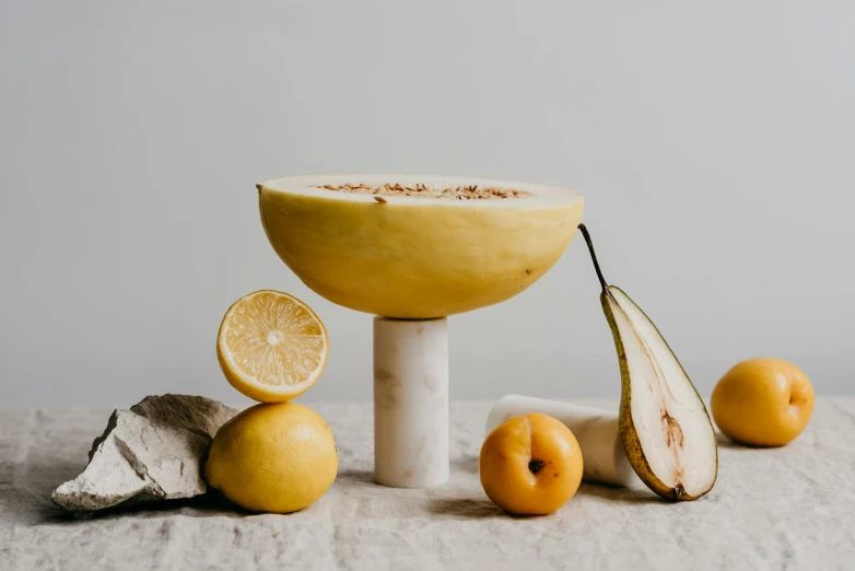 a bowl of fruit sitting on top of a table, inspired by William Yellowlees, unsplash, baroque, cycladic sculptural style, high quality product image”, on a marble pedestal, yellow aura