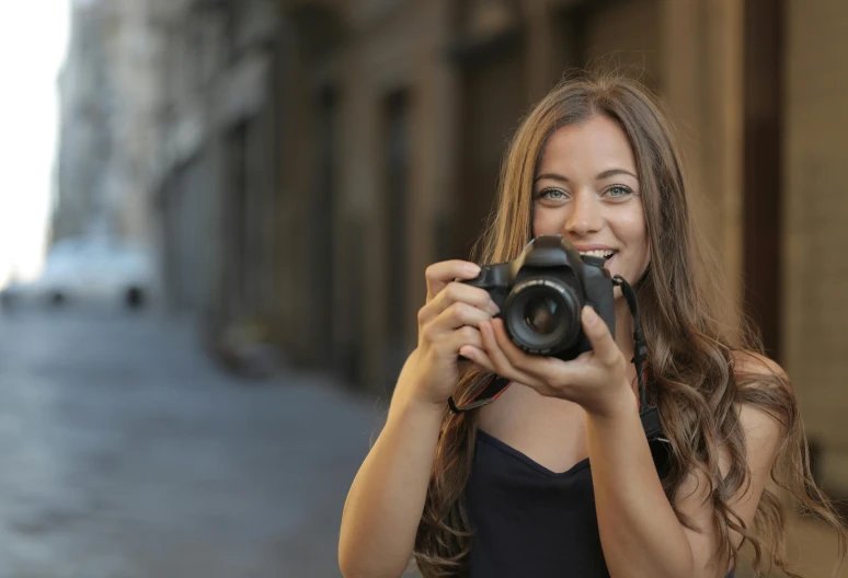 a woman taking a picture with a camera, pexels contest winner, italian looking emma, smiling at camera, street pic, headshot and bodyshot