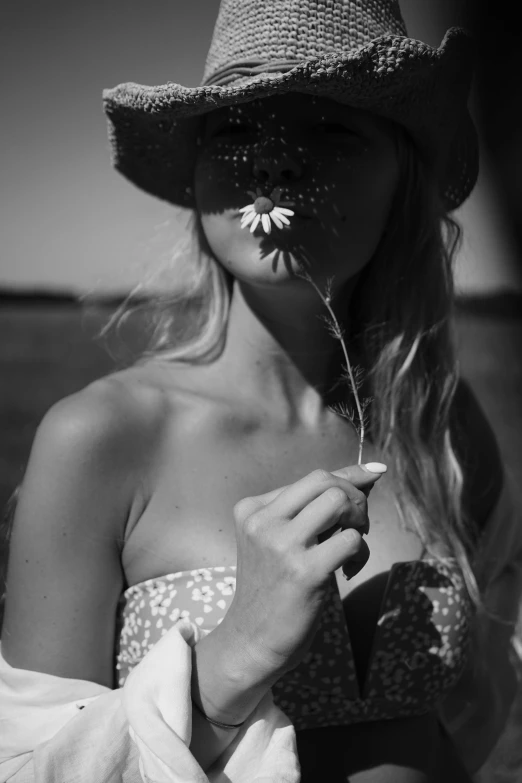 a black and white photo of a woman with a flower in her mouth, tumblr, hat covering eyes, magical summer, (beautiful) girl, sunburn