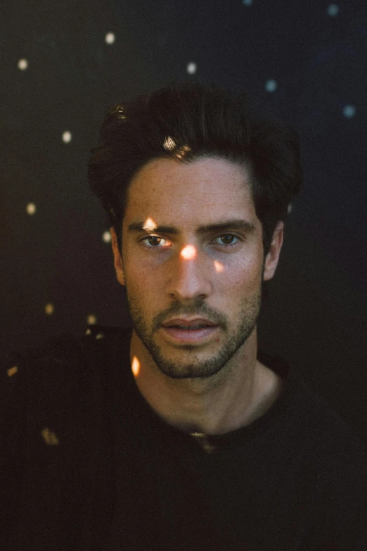 a man standing in front of a black background, an album cover, inspired by Pablo Munoz Gomez, photorealism, handsome attractive face, greg rutowski, light show, a still of an ethereal