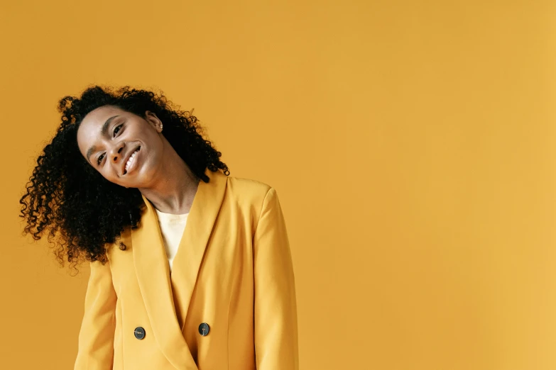 a woman with curly hair wearing a yellow blazer, trending on pexels, minimalism, with a happy expression, subject detail: wearing a suit, thumbnail, diverse