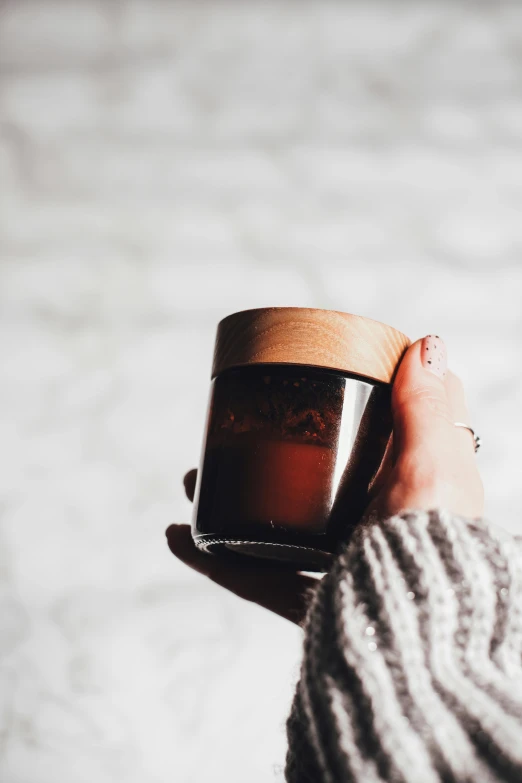 a person holding a cup of coffee in their hand, waxy candles, maple syrup fluid, dwell, detailed product image