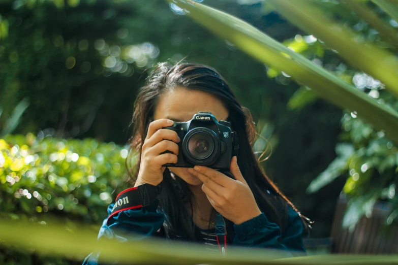 a woman taking a picture of herself with a camera, a picture, inspired by Elsa Bleda, unsplash contest winner, amongst foliage, macro photography 8k, medium format, zoo photography