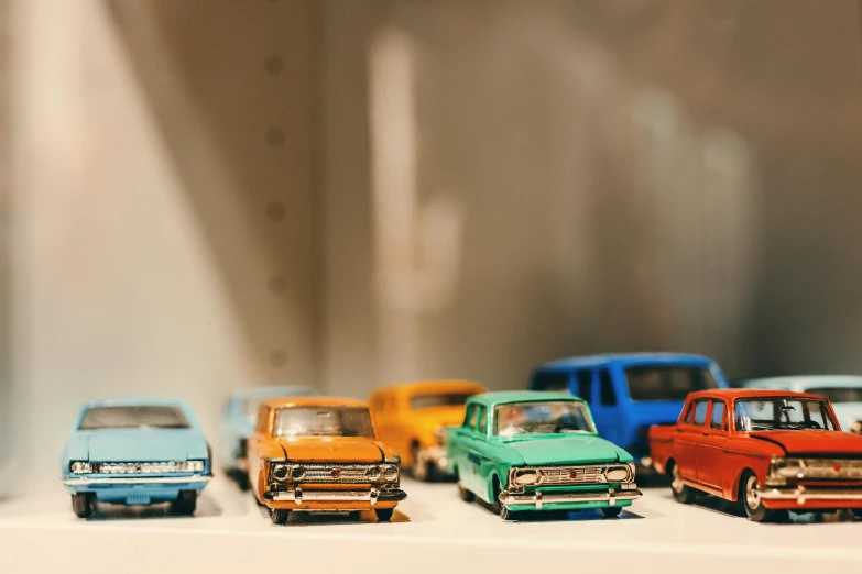 a row of toy cars sitting on top of a shelf, trending on unsplash, photorealism, 🚿🗝📝