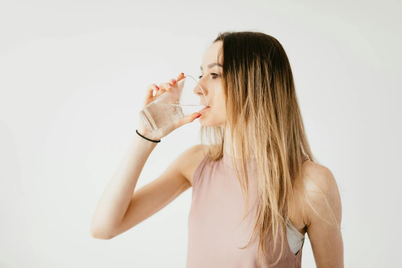 a woman drinking a glass of water, pexels contest winner, in front of white back drop, sydney sweeney, health supporter, very thin