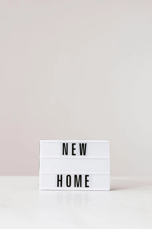 a new home sign sitting on top of a white table, unsplash, new objectivity, light box, #trending, vhs, multi-part