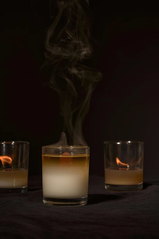 a couple of glasses sitting on top of a table, with smoke, candle wax, dramatic product shot, ignant