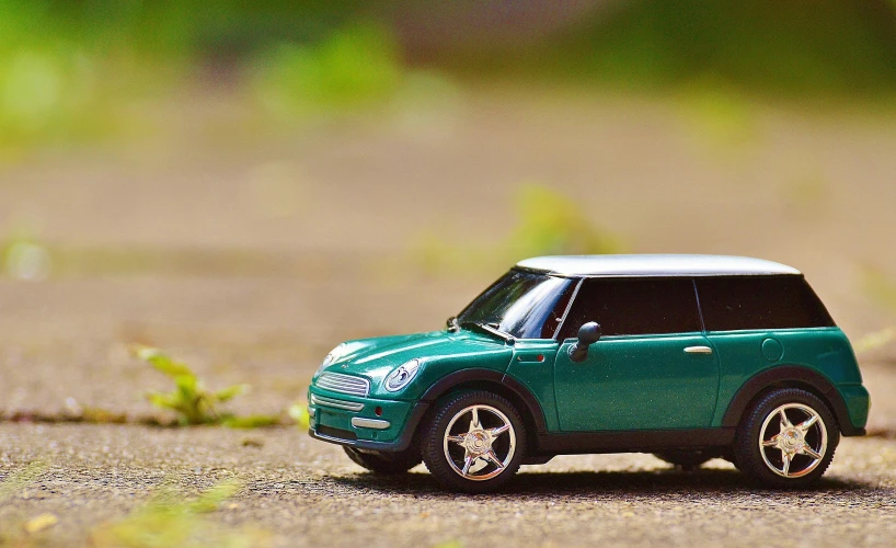 a toy car that is sitting on the ground, pexels contest winner, photorealism, lush green, mini cooper, highway, side profile shot