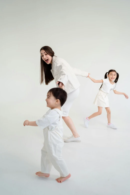 a woman and two children are playing with each other, an album cover, inspired by Fei Danxu, pexels contest winner, white studio, wearing white clothes, at full stride, ross tan