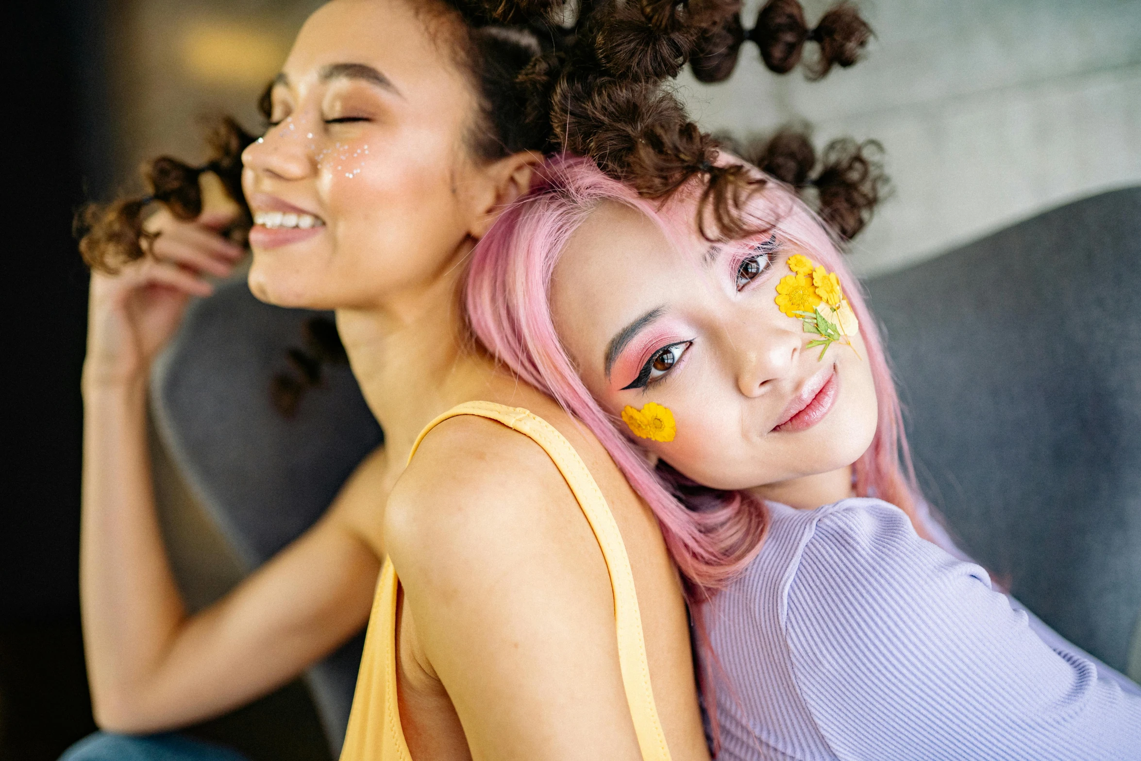 a couple of women sitting on top of a couch, trending on pexels, antipodeans, kawaii hair style, yellow makeup, flower power, asian descent