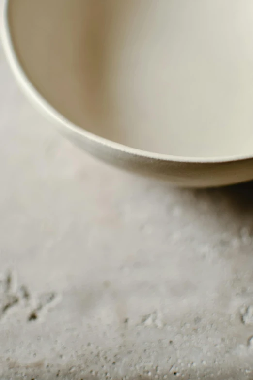 a white bowl sitting on top of a counter, a picture, inspired by Agnes Martin, trending on unsplash, detail texture, ivory rococo, powder, looking left