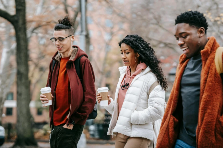 a group of people walking down a street, trending on pexels, brown skinned, autumnal, drinking a strawberry iced latte, male teenager