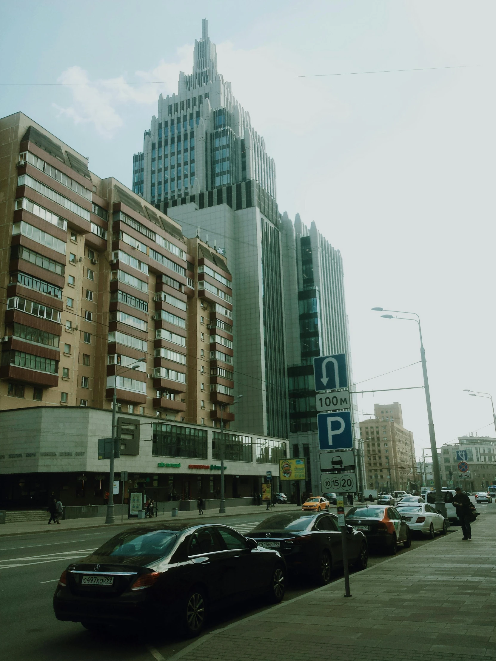 a group of cars driving down a street next to tall buildings, by Andrei Kolkoutine, pexels contest winner, socialist realism, 2000s photo, russian architecture, standing on street corner, 000 — википедия