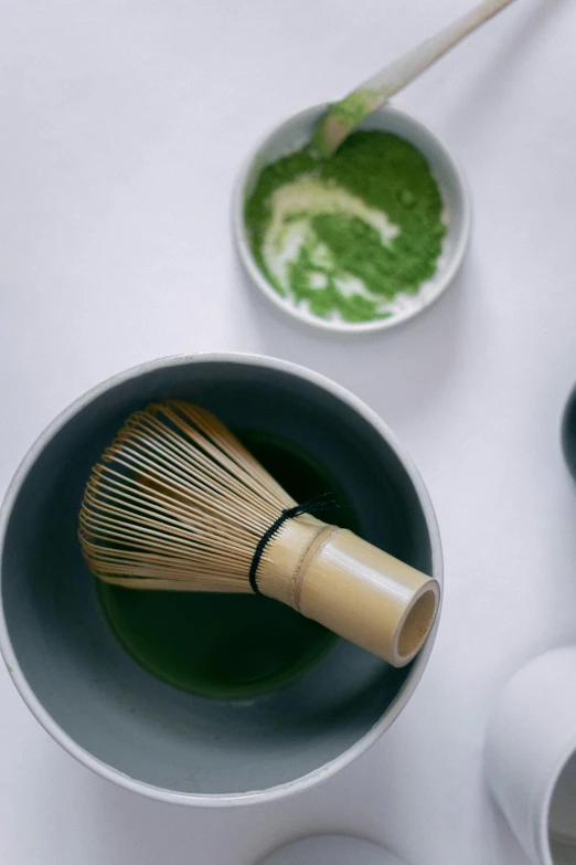 a bowl of green tea with a whisk in it, inspired by Kanō Shōsenin, trending on unsplash, brushes, epicurious, snapchat photo, made of bamboo