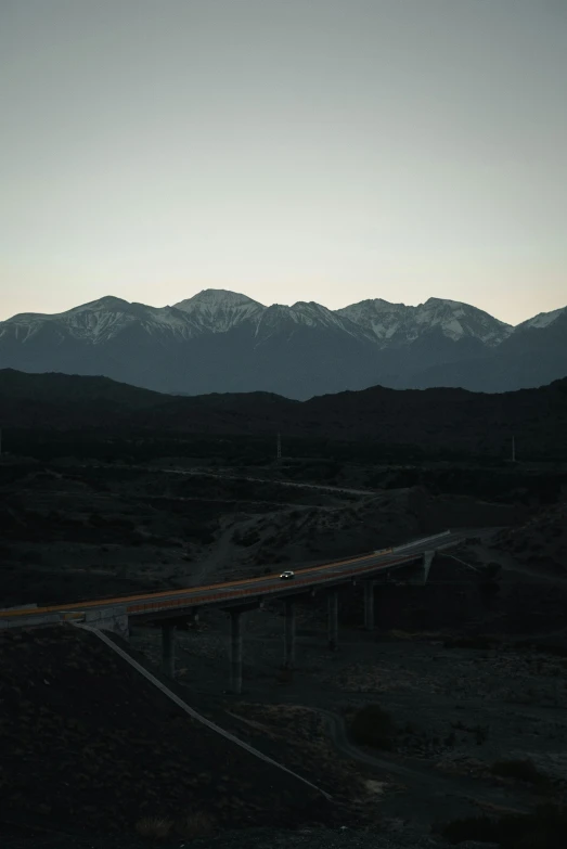 a highway in the middle of a desert with mountains in the background, inspired by Elsa Bleda, hurufiyya, on a bridge, dark setting, new zealand, 2022 photograph