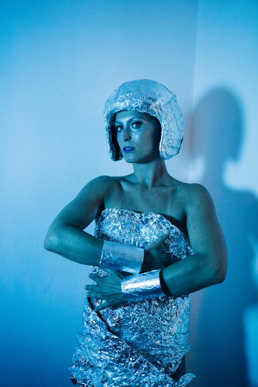 a woman in a silver dress posing for a picture, inspired by Cindy Sherman, holography, wearing an astronaut helmet, moody blue lighting, promo photo, mirka andolfo