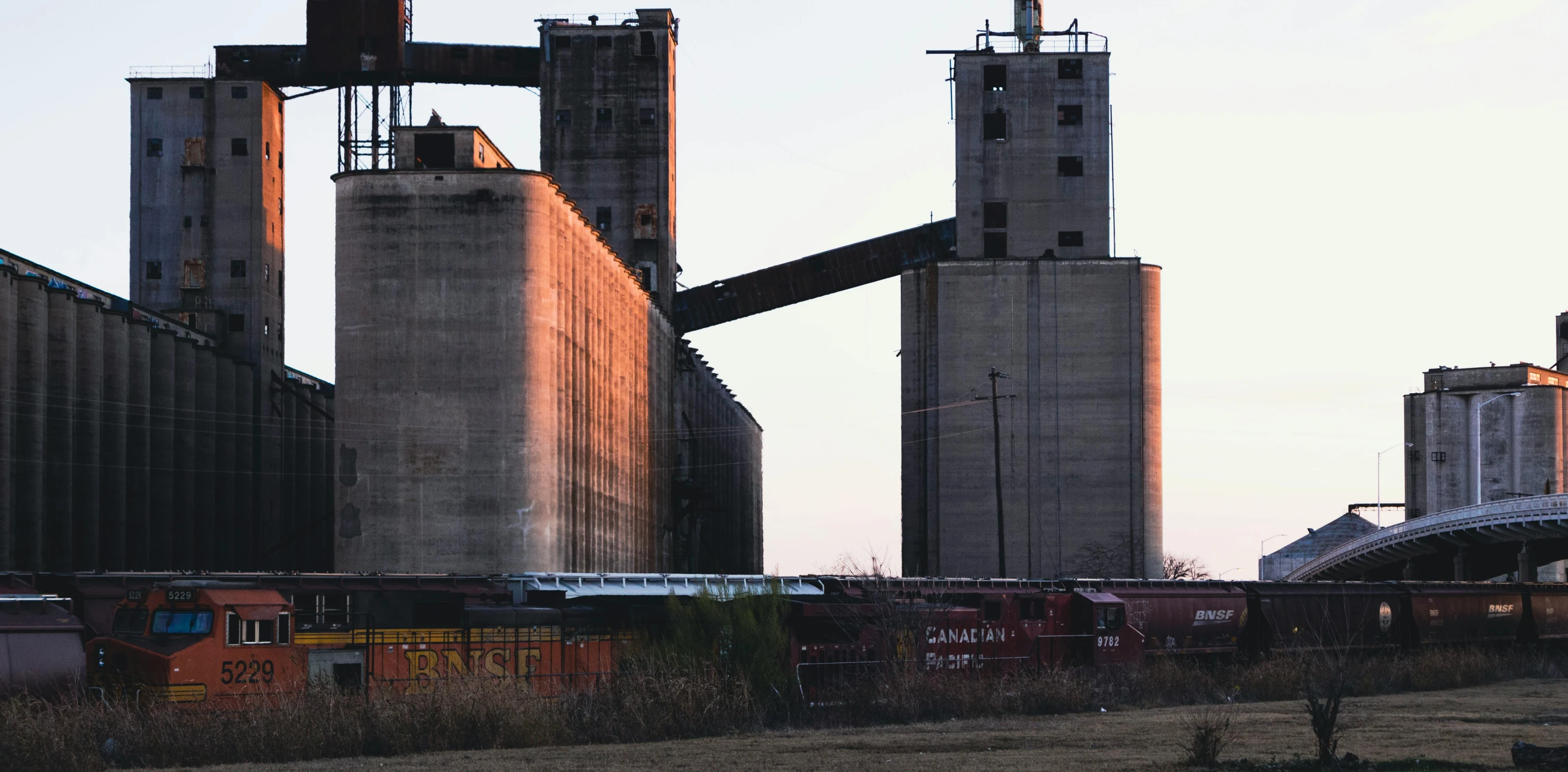a large long train on a steel track, by Dan Frazier, pexels contest winner, brutalism, silo, two towers, old american midwest, seen from outside