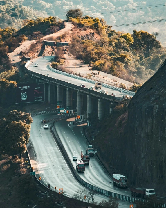 a group of cars driving down a road next to a mountain, by Alejandro Obregón, pexels contest winner, renaissance, lots of bridges, in sci - fi mumbai, thumbnail, flatlay