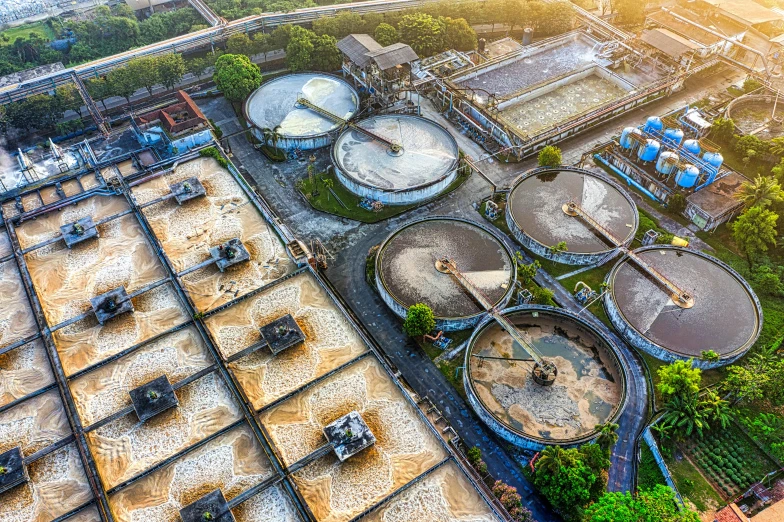 a group of tanks sitting on top of a lush green hillside, by Kurt Roesch, pexels contest winner, renaissance, biroremediation plant, sewer, drone photograph, sewage