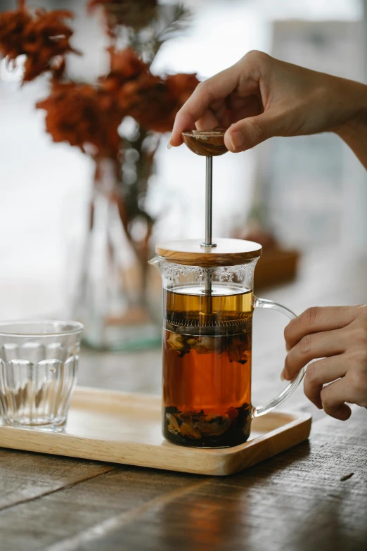 a person sitting at a table with a cup of tea, inside a glass jar, pouring, square, jakarta