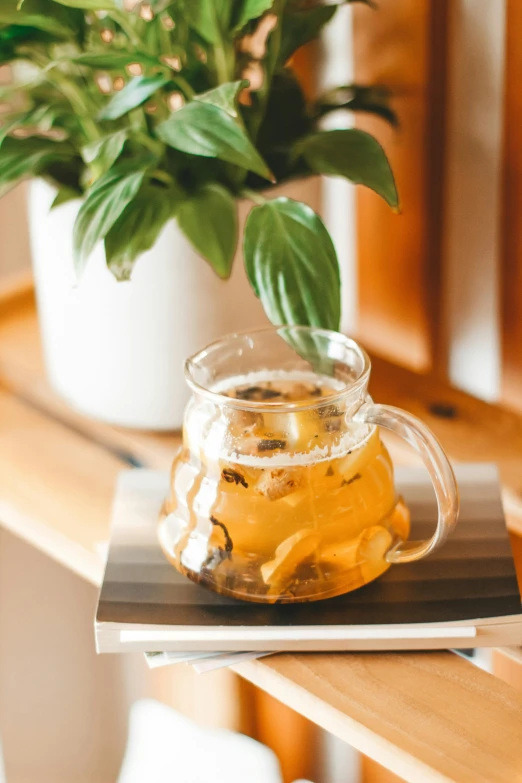 a cup of tea sitting on top of a wooden table, trending on unsplash, renaissance, plants in glass vase, basil, manuka, flowy