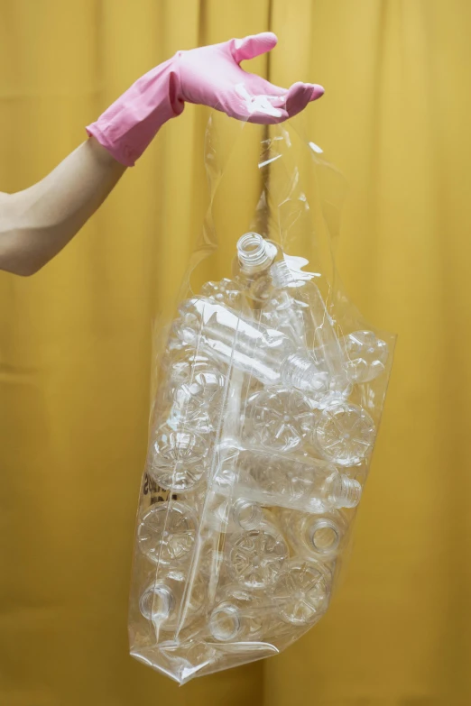 a person in pink gloves holding a plastic bag, inspired by Sarah Lucas, unsplash, plasticien, crystal column, sitting on top of a cryopod, transparent liquid, iv pole