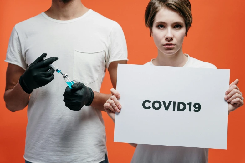 a man and a woman holding a sign that says covid199, trending on pexels, holding syringe, without text, profile pic, 2263539546]