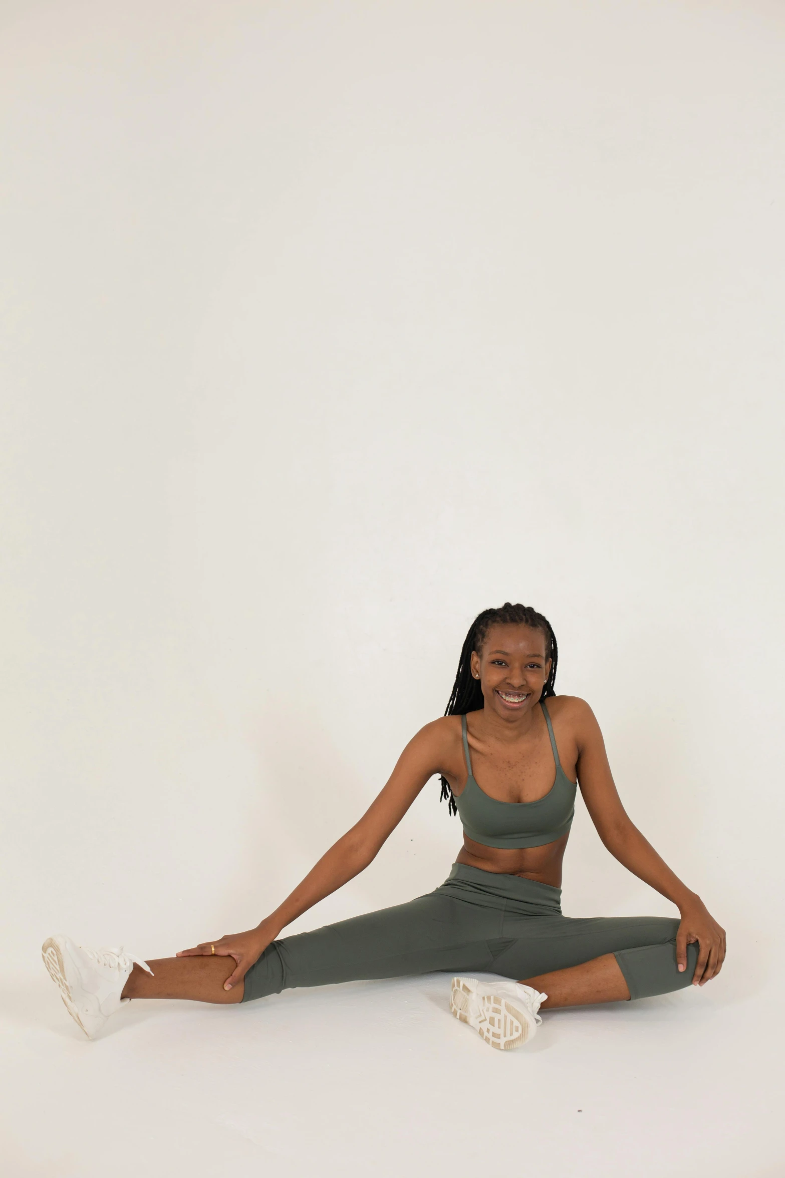 a woman sitting in the middle of a yoga pose, by Dulah Marie Evans, cute sportswear, muted green, dramatic smile pose, low quality photo