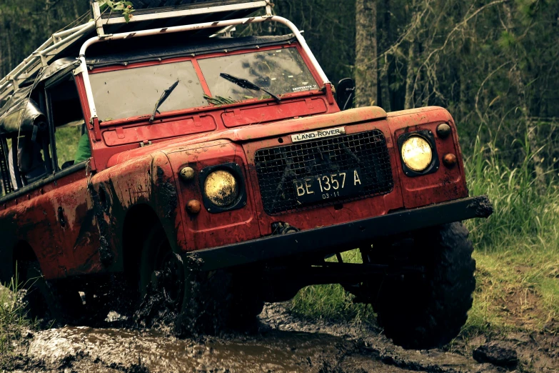 a red land rover driving down a muddy road, a cartoon, unsplash, sumatraism, classic cars, close - up photo, old color photo, ultra 4k