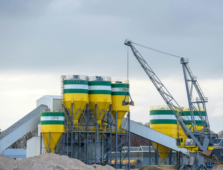 a large crane sitting on top of a pile of dirt, a photo, shutterstock, plasticien, yellow and green scheme, silo, vessels, grey