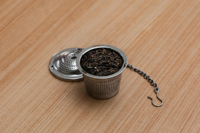 a metal tea strainer sitting on top of a wooden table, a digital rendering, unsplash, hurufiyya, hibernation capsule close-up, miniature product photo, chain mail, 8k 4k