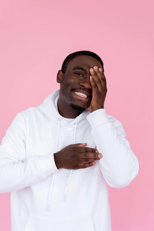 a man in a white hoodie on a pink background, by Cosmo Alexander, trending on pexels, happening, giggling, ( ( dark skin ) ), hey buddy, without text
