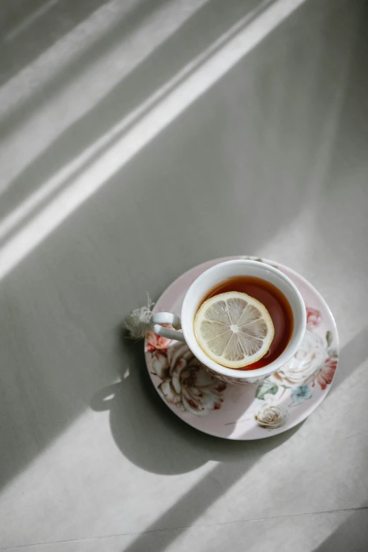 a cup of tea with a lemon on a saucer, by Felicity Charlton, trending on unsplash, sun puddle, white and pink cloth, portrait photo, 15081959 21121991 01012000 4k