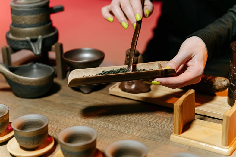 a person preparing a cup of tea on a table, inspired by Gatōken Shunshi, trending on pexels, mortar and pestle, melbourne, carrying a tray, 🦩🪐🐞👩🏻🦳