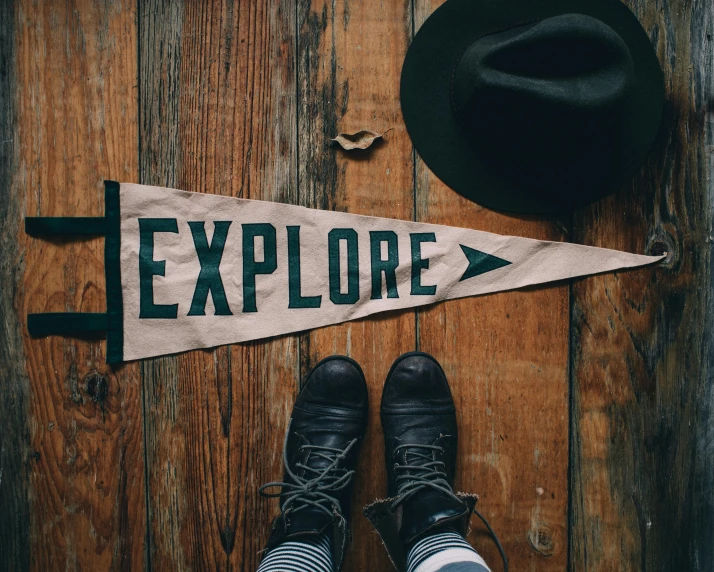 a pair of black shoes sitting on top of a wooden floor, by Emma Andijewska, trending on unsplash, graffiti, wearing a travel hat, cloth banners, explorers, camera looking up at her
