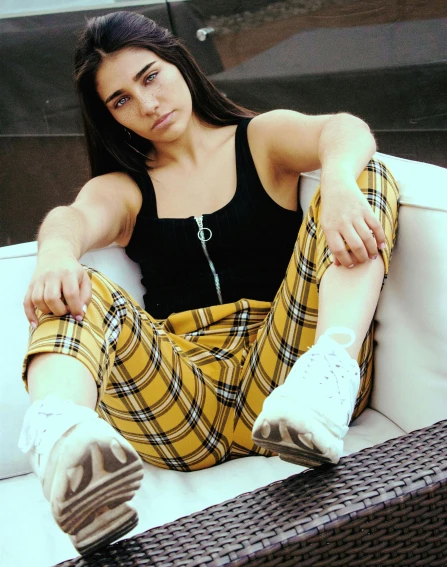 a woman sitting on top of a white couch, inspired by Elsa Bleda, trending on pexels, hurufiyya, black and yellow tracksuit, wearing a flannel shirt, non binary model, attractive photo