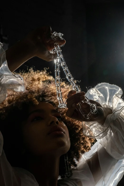 a woman in a white shirt is holding a chandelier, inspired by Cerith Wyn Evans, trending on pexels, imaan hammam, made out of clear plastic, jewelry photography, sza