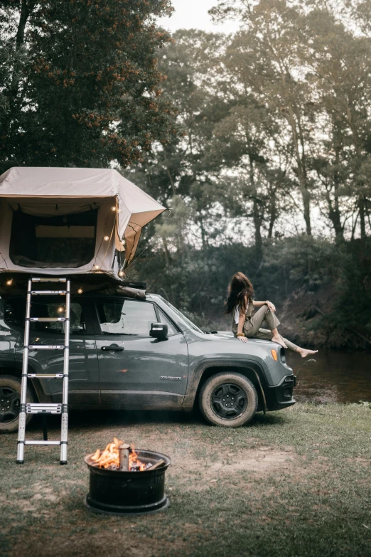 a woman sitting on top of a truck next to a camper, unsplash contest winner, renaissance, jeep wrangler, in savannah, barrel fires and tents, car jumping