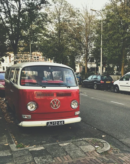 a red and white vw bus parked on the side of the road, by Lucia Peka, trending on unsplash, amsterdam, square, high quality photo, during autumn