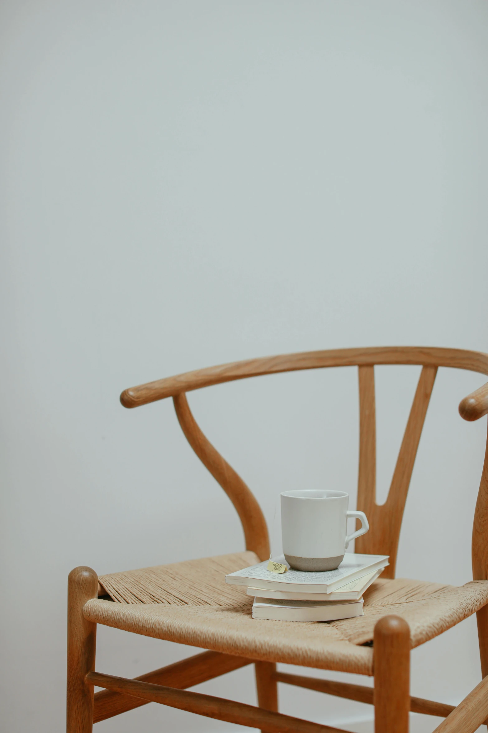 a wooden chair with a cup on top of it, inspired by Constantin Hansen, trending on unsplash, minimalism, thin antlers, reading, close up portrait shot, 15081959 21121991 01012000 4k