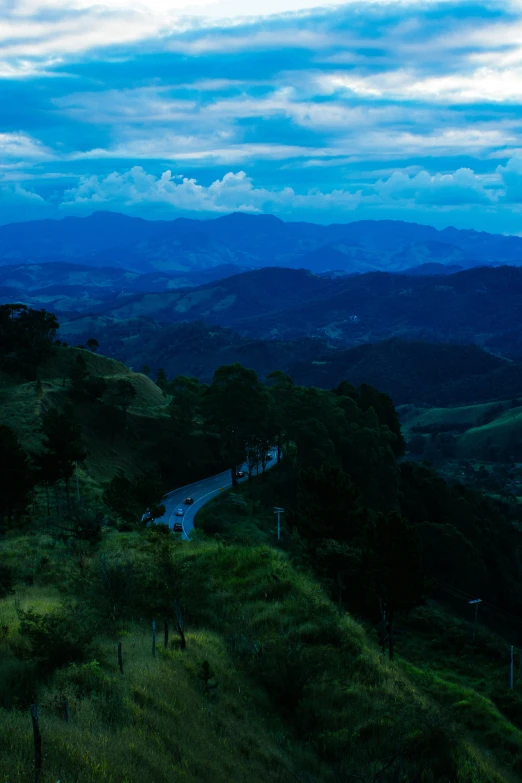 a view of the mountains from the top of a hill, by Niklaus Manuel, colombia, ominous evening, road, blue