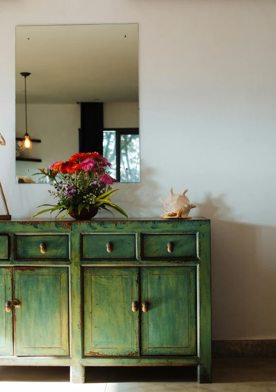 a vase of flowers sitting on top of a green dresser, unsplash, modernism, coastal, rustic setting, server, units