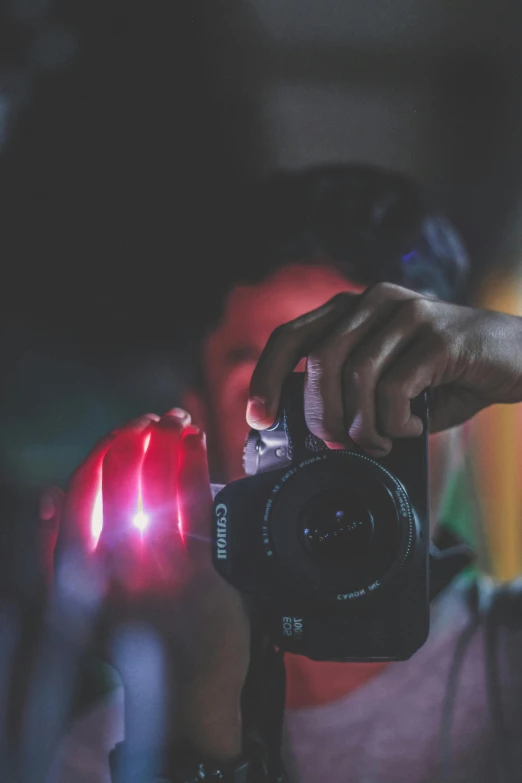 a person taking a picture with a camera, pexels contest winner, light emitting from fingertips, red and blue lighting, overexposed flash, shot with a canon