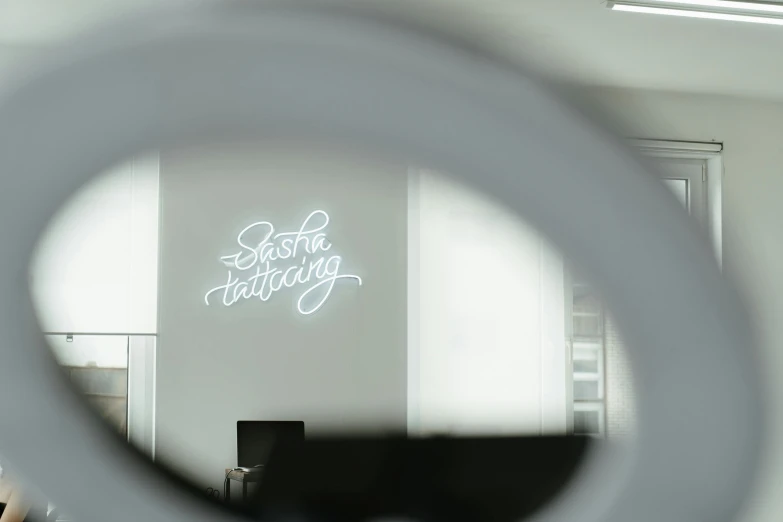 a reflection of a neon sign in a mirror, a tattoo, by Sebastian Spreng, trending on unsplash, light and space, in a meeting room, on a gray background, a glowing halo, in white room