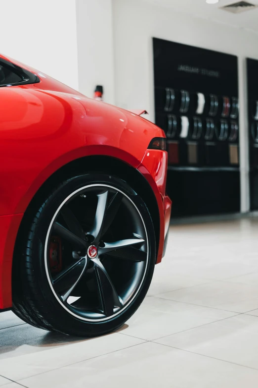 a red sports car parked in a showroom, pexels contest winner, black wheel rims, jaguar, detailed high resolution, thumbnail