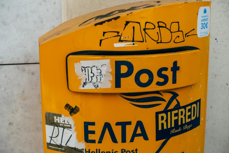 a yellow post box with stickers on it, inspired by Mimmo Rotella, pexels contest winner, mail art, greece, pbr, port, graffiti paint