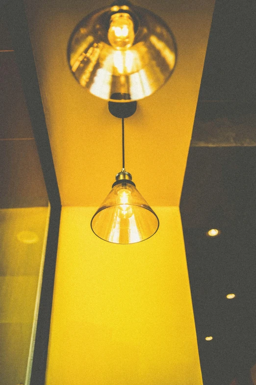 a light that is on in a room, by Niko Henrichon, unsplash, yellow details, cafe lighting, taken in the 2000s, light cone
