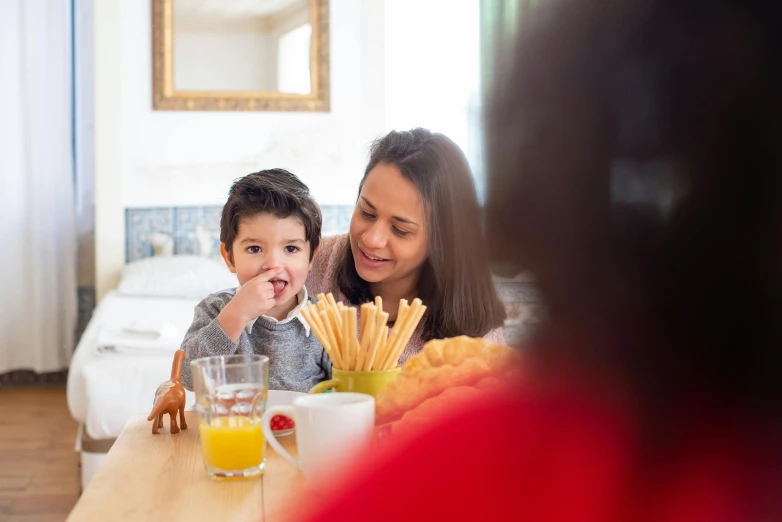 a woman sitting at a table with a child, pexels contest winner, breakfast, avatar image, hispanic, close - up photo