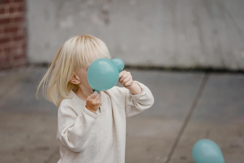 a little girl holding a blue balloon in front of her face, by Nina Hamnett, pexels contest winner, seafoam green, playing games, on grey background, hammershøi