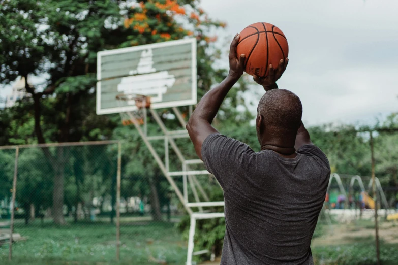 a man standing on top of a basketball court holding a basketball, by Matija Jama, pexels contest winner, at a park, shaq, tapping in to something greater, 15081959 21121991 01012000 4k